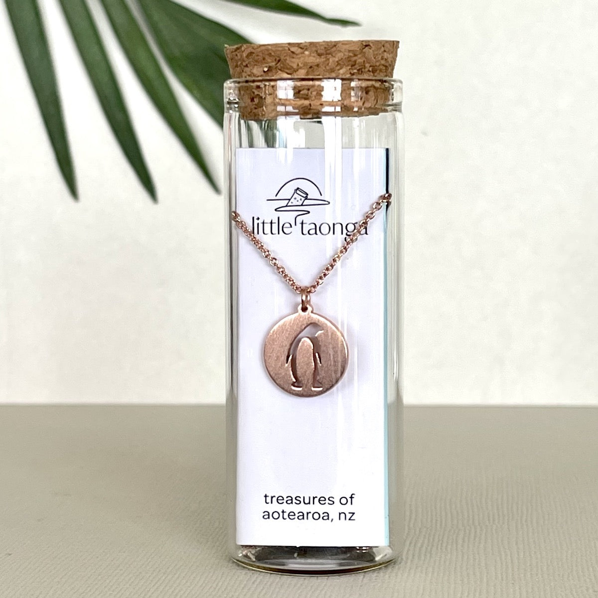 rose gold penguin necklace in a glass bottle